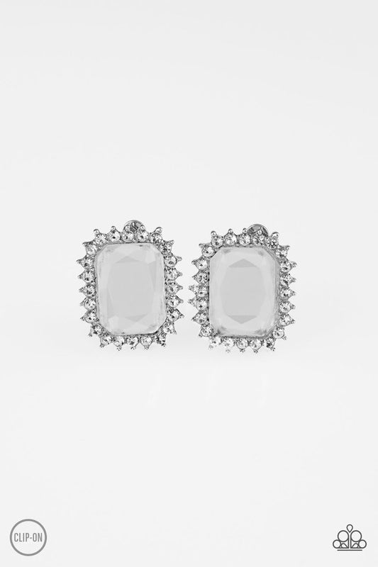 Featuring a regal emerald style cut, a dramatic white gem is pressed into the center of a silver frame radiating with glassy white rhinestones for a show-stopping look. Earring attaches to a standard clip-on fitting.  Sold as one pair of clip-on earrings.