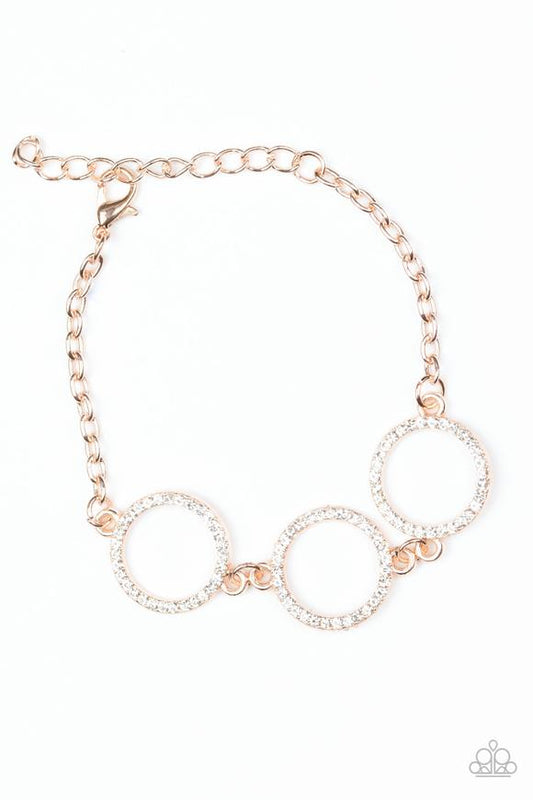 Encrusted in glassy white rhinestones, three glittery rose gold rings link across the wrist for a glamorous look. Features an adjustable clasp closure.  Sold as one individual bracelet.