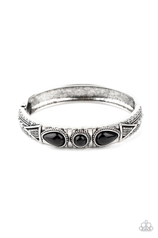 Studded in tribal inspired designs, the top of an antiqued silver cuff-like bangle is embellished with shiny black beads for a colorful look. Features a hinged closure.  Sold as one individual bracelet.
