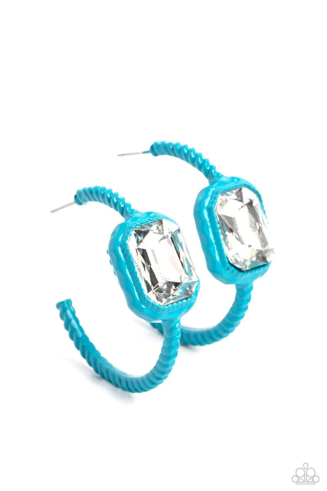 Textured metal dipped in a vibrant blue shade curls around the ear for a fashion-forward statement. A radiant, emerald-cut white gem is embedded near the top of the curve of color for a touch of sparkle. Earring attaches to a standard post fitting. Hoop measures approximately 1 1/2" in diameter.  Sold as one pair of hoop earrings.