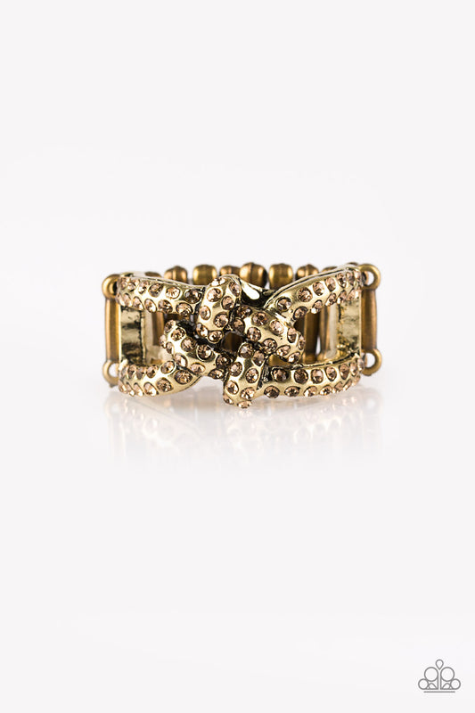 Encrusted in golden topaz rhinestones, shimmery brass bars crisscross across the finger, coalescing into a bold square knot atop the finger. Features a stretchy band for a flexible fit.  Sold as one individual ring.
