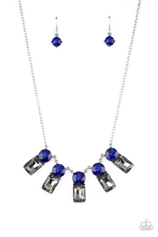 A sparkly row of oversized blue gems regally sit atop emerald cut smoky rhinestone bases as they delicately link along a dainty silver chain below the collar, resulting in a royal glamorous centerpiece. Features an adjustable clasp closure.  Sold as one individual necklace. Includes one pair of matching earrings.