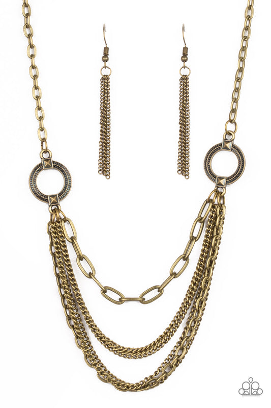Ornate brass hoops give way to mismatched brass chains below the collar for an edgy industrial look. Features an adjustable clasp closure.  Sold as one individual necklace. Includes one pair of matching earrings.