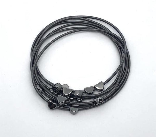 Dainty black hearts slide along interlocking stretchy spring-like wires, creating whimsical layers across the wrist.

Sold as one individual bracelet.