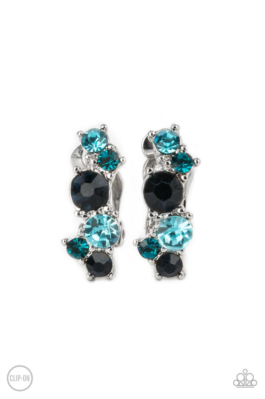 Varying in shades of blue, mismatched rhinestones delicately coalesce into a dainty frame for a colorfully sparkly display. Earring attaches to a standard clip-on fitting.  Sold as one pair of clip-on earrings.