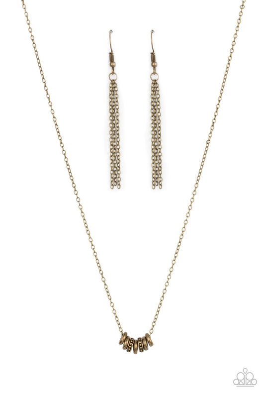 An antiqued collection of smooth and studded brass rings glide along a dainty brass chain below the collar, creating a minimalist inspired look. Features an adjustable clasp closure.  Sold as one individual necklace. Includes one pair of brass fringe earrings.