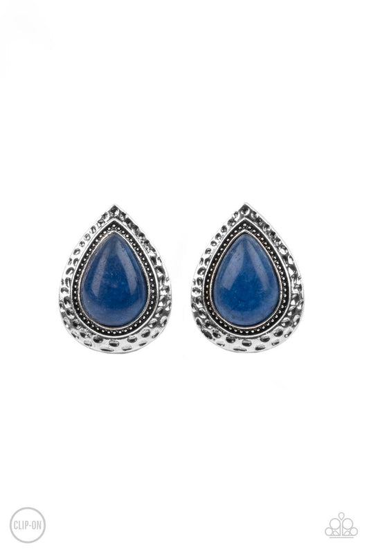 A teardrop lapis lazuli stone is pressed into the center of a hammered silver frame, creating a rustic display. Earring attaches to a standard clip-on fitting.  Sold as one pair of clip-on earrings.