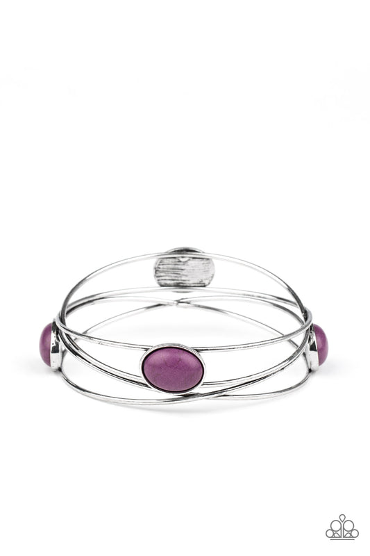 Dotted in oval purple stones, a stack of shimmery silver bangles haphazardly layer into a one-of-a-kind bracelet.  Sold as one individual bracelet.