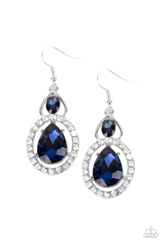 An oversized blue teardrop gem is nestled inside a ring of glassy white rhinestones that attaches to an airy silver fitting adorned with a blue oval rhinestone. Earring attaches to a standard fishhook fitting.  Sold as one pair of earrings.