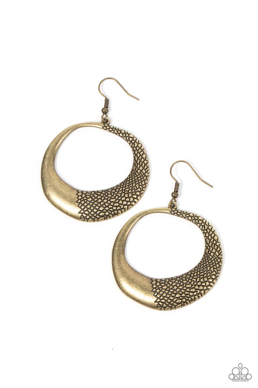 One side of an asymmetrical&nbsp;brass hoop is embossed in rugged pebble like texture, culminating in a wildly abstract frame. Earring attaches to a standard fishhook fitting.  Sold as one pair of earrings.