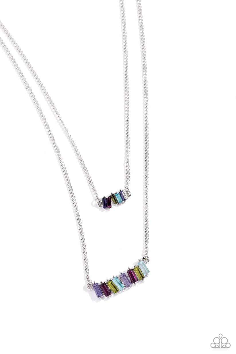 Two strands of dainty silver chains fall into tiered layers as they cascade down the chest. Featuring various multicolored shades, emerald-cut gems set in silver-pronged fittings dance along each chain for a dizzying display. Features an adjustable clasp closure.  Sold as one individual necklace. Includes one pair of matching earrings.