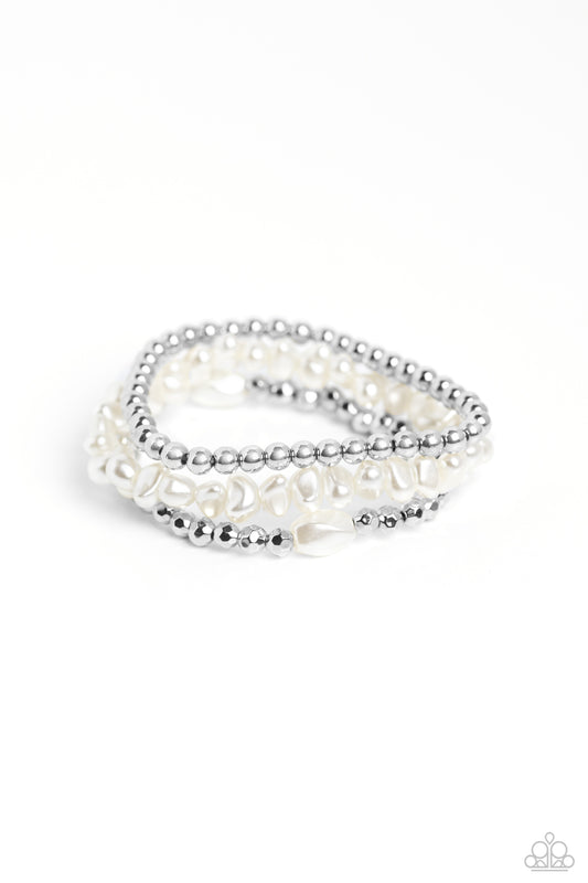 Coalescing into a light-reflecting stack up the wrist, silver beads, baroque white pearl beads, and faceted silver beads with a solitaire white pearl bead wrap around the wrist on elastic stretchy bands for a fashionable display.

Sold as one set of three bracelets.