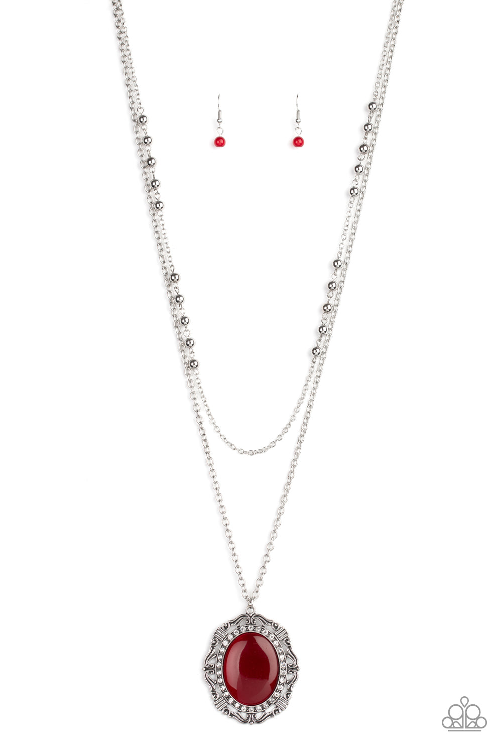 Two shimmery silver chains layer down the chest. Dotted with dainty silver beads, the uppermost strand gives way to a classic silver chain featuring a vintage inspired pendant dotted with an oversized red cat’s eye stone center ringed in dainty white rhinestones. Features an adjustable clasp closure.  Sold as one individual necklace. Includes one pair of matching earrings.