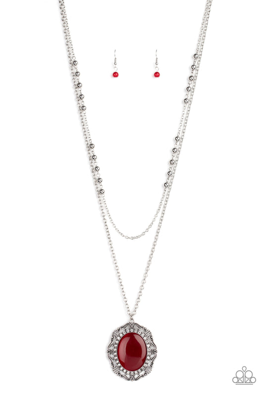 Two shimmery silver chains layer down the chest. Dotted with dainty silver beads, the uppermost strand gives way to a classic silver chain featuring a vintage inspired pendant dotted with an oversized red cat’s eye stone center ringed in dainty white rhinestones. Features an adjustable clasp closure.  Sold as one individual necklace. Includes one pair of matching earrings.