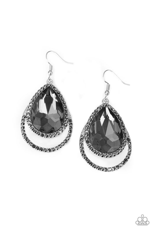 A dramatically oversized smoky teardrop gem is pressed into a doubled silver frame encrusted in countless white rhinestones for a blinding look. Earring attaches to a standard fishhook fitting.  Sold as one pair of earrings.