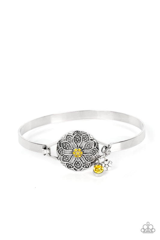 Studded silver petals bloom out from a dainty Daffodil rhinestone center, blooming into an embossed floral frame that hinges to the center of a dainty bangle-like bracelet. A dainty silver flower and Daffodil rhinestone accent dangles from the flowery centerpiece, adding playful movement to the whimsical display. Features a hinged closure.  Sold as one individual bracelet.