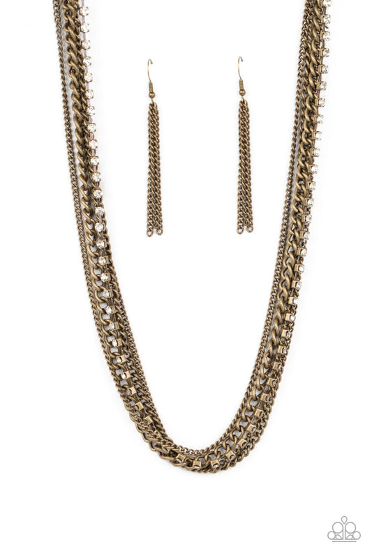 A mashup of brass chains collides with a strand of sparkling white rhinestones encased in brass fittings. The contrast of gritty brass finishes and shimmery accents creates a brilliant display of grunge and glitz as the strands layer across the chest in an epic finish. Features an adjustable clasp closure.  Sold as one individual necklace. Includes one pair of matching earrings.