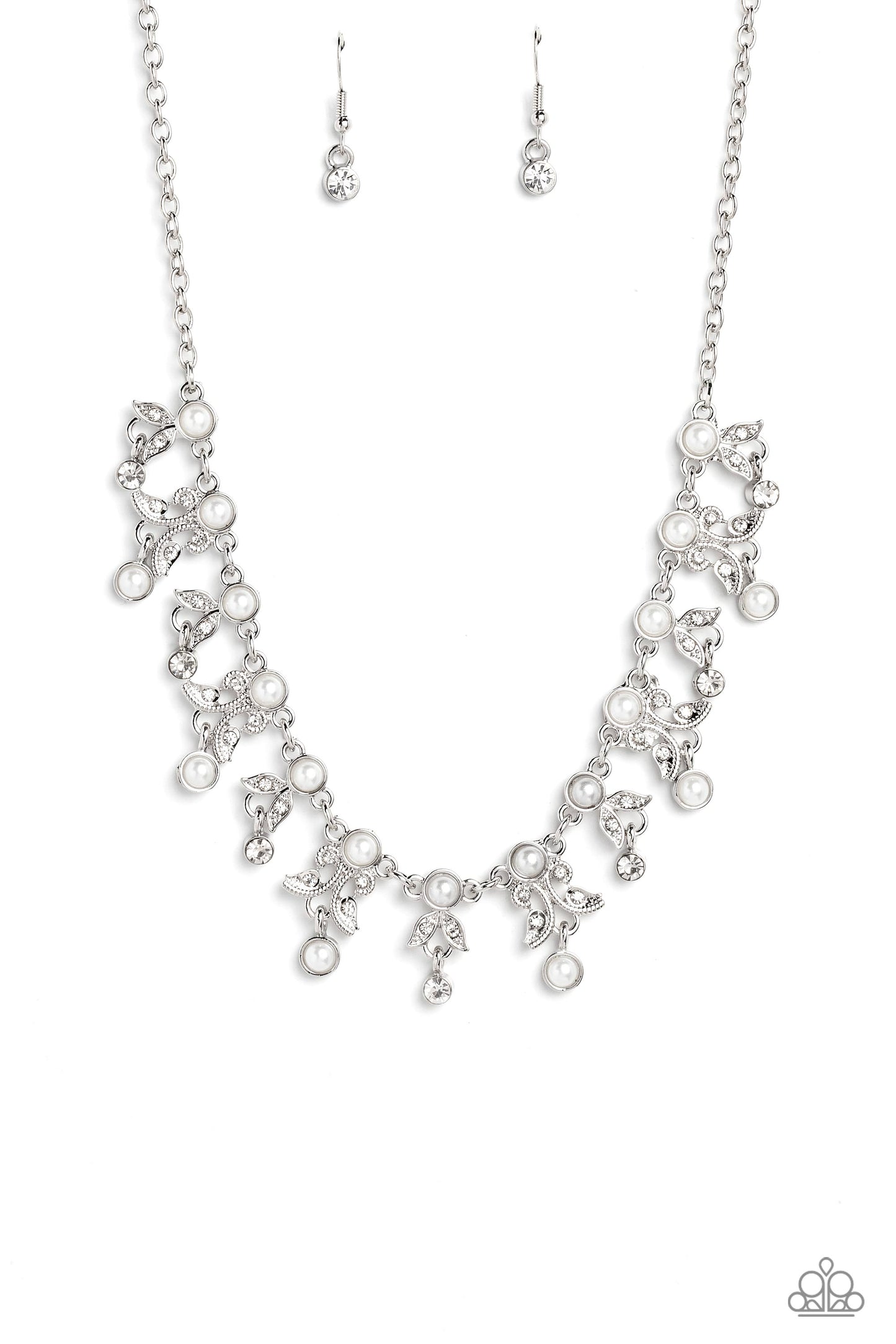 Infused along a classic silver chain, a row of white pearls, pressed into silver frames, stands out against the collar for a touch of refinement. Dangling below the row of white pearls, a shimmery collection of leaf-like filigree and detailing, studded with dainty white rhinestones and silver studs, adds a botanical element to the elegant display. Crystal-like white gems and white pearls encased in silver frames, dangle below every other botanical charm, rounding out the design with whimsical movement. 