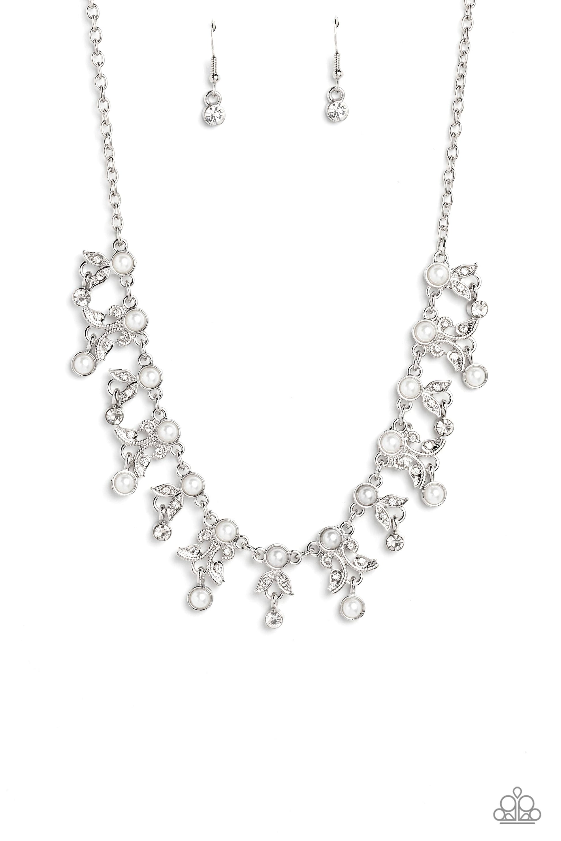 Infused along a classic silver chain, a row of white pearls, pressed into silver frames, stands out against the collar for a touch of refinement. Dangling below the row of white pearls, a shimmery collection of leaf-like filigree and detailing, studded with dainty white rhinestones and silver studs, adds a botanical element to the elegant display. Crystal-like white gems and white pearls encased in silver frames, dangle below every other botanical charm, rounding out the design with whimsical movement. 