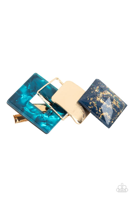 Infused with gold sparkles, a faceted blue acrylic frame delicately overlaps with a golden square and a blue shell-like frame across the front of a classic gold bar for a deco inspired finish. Features a standard hair clip on the back.  Sold as one individual hair clip. hair clip