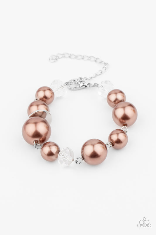 A glamorous collection of white crystal-like beads, shiny silver ovals, and oversized brown pearls delicately link around the wrist creating an effortless glow. Features an adjustable clasp closure.

Sold as one individual bracelet.