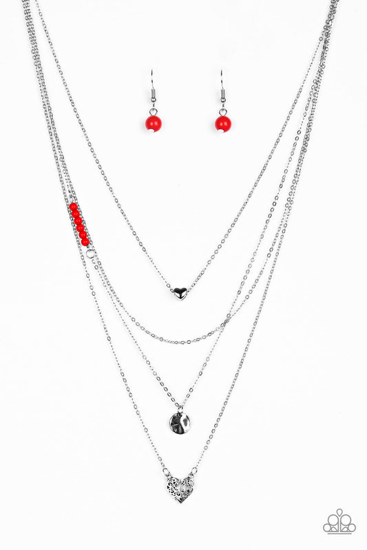 Shimmery silver layers cascade below the collar. Infused with hints of fiery red beading, dainty silver hearts and a delicately hammered silver disc swing from the bottoms of the chains for a whimsical finish. Features an adjustable clasp closure. Sold as one individual necklace. Includes one pair of matching earrings.  Sold as one individual necklace. Includes one pair of matching earrings.