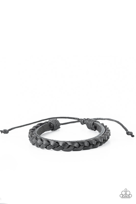 Strands of black leather cording braid across the front of a dainty black leather band, creating a rustic display around the wrist. Features an adjustable sliding knot closure.  Sold as one individual bracelet.