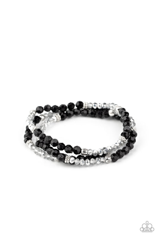 A dainty collection of glittery black and metallic flecked crystal-like beads join mismatched silver accents along stretchy bands around the wrist, creating whimsical layers.

Sold as one set of three bracelets.