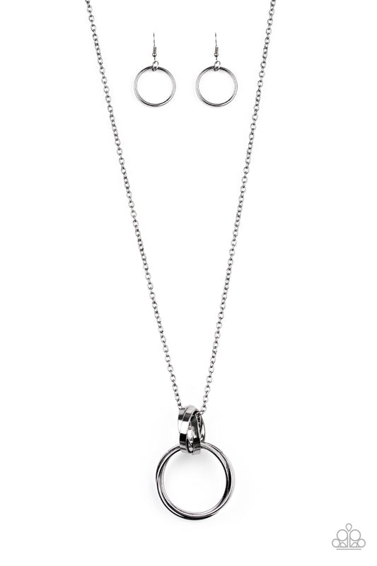 Trios of exaggerated gunmetal rings link at the bottom of a lengthened gunmetal chain, creating a dramatic industrial pendant. Features an adjustable clasp closure.  Sold as one individual necklace. Includes one pair of matching earrings.
