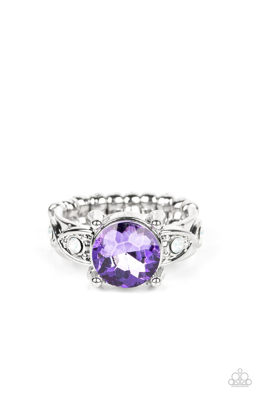 An oversized purple gem is nestled between silver prongs atop a band swirling with silver ribbons and dotted with dainty opal rhinestones, resulting in a stellar sparkle atop the finger. Features a dainty stretchy band for a flexible fit.  Sold as one individual ring.