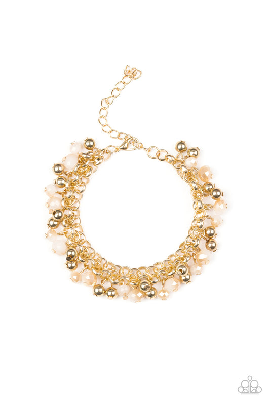 Dipped into a golden metallic shimmer, faceted white beads and classic gold beads swing from interlocking gold chains, creating a refined fringe around the wrist. Features an adjustable clasp closure.

Sold as one individual bracelet.