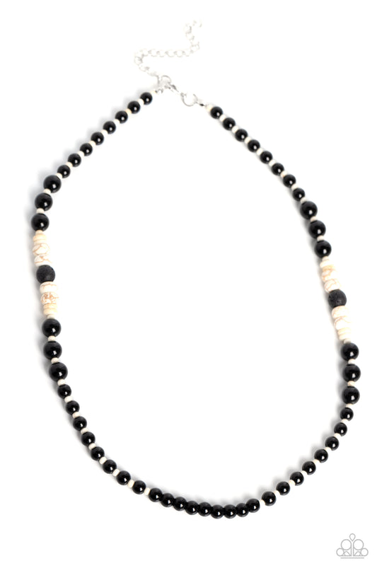 Strung along the entirety of a black cord, white seed beads, black beads, white stone discs, and earthy lava rock beads coalesce down the neckline into an earthy, urban statement. Features an adjustable clasp closure. As the stone elements in this piece are natural, some color variation is normal.  Sold as one individual necklace.