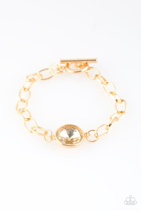 An oversized white gem attaches to a bold gold chain, creating a dramatic centerpiece atop the wrist. Features an adjustable clasp closure.  Sold as one individual bracelet.