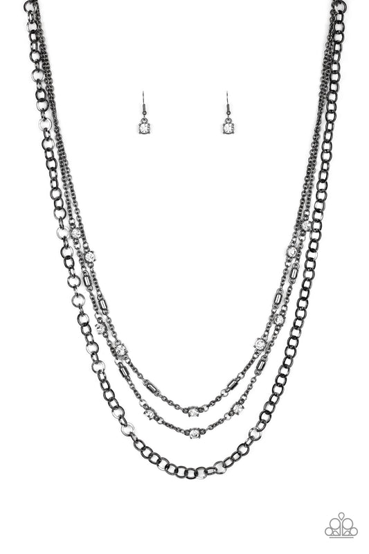 Dotted with glassy white rhinestones and glistening gunmetal accents, a collision of mismatched gunmetal chains layer down the chest for a refined flair. Features an adjustable clasp closure.  Sold as one individual necklace. Includes one pair of matching earrings.