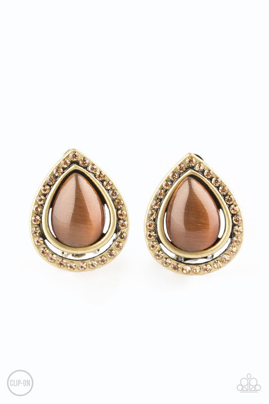 Encrusted in golden topaz rhinestones, a radiant brass ribbon spins around a glowing brown moonstone center, creating a refined teardrop. Earring attaches to a standard clip-on fitting.  Sold as one pair of clip-on earrings.