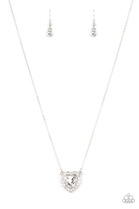 Glittery white rhinestones encircle a white heart shaped gem, creating a flirty pendant below the collar. Features an adjustable clasp closure.  Sold as one individual necklace. Includes one pair of matching earrings.