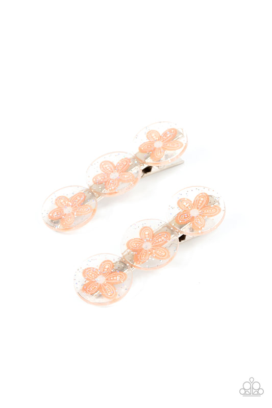 Sprinkled in silvery sparkles, trios of orange flower adorned acrylic discs join into a whimsical pair of hair clips. Features standard hair clips on the back.  Sold as a set of two hair clips.