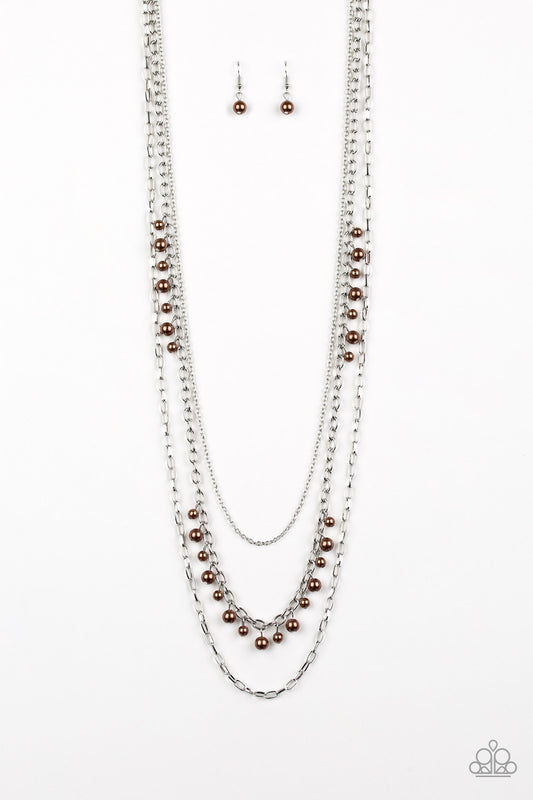 Three mismatched silver chains layer down the chest. Dainty brown pearls cascade down one silver chain, adding a flirty twist to the timeless pearl palette. Features an adjustable clasp closure.  Sold as one individual necklace. Includes one pair of matching earrings.