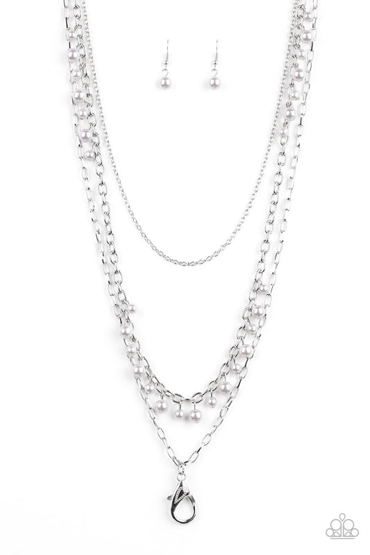 Three mismatched silver chains layer down the chest. Dainty silver pearls cascade down one silver chain, creating a refined fringe. A lobster clasp hangs from the bottom of the design to allow a name badge or other item to be attached. Features an adjustable clasp closure.  Sold as one individual lanyard. Includes one pair of matching earrings.