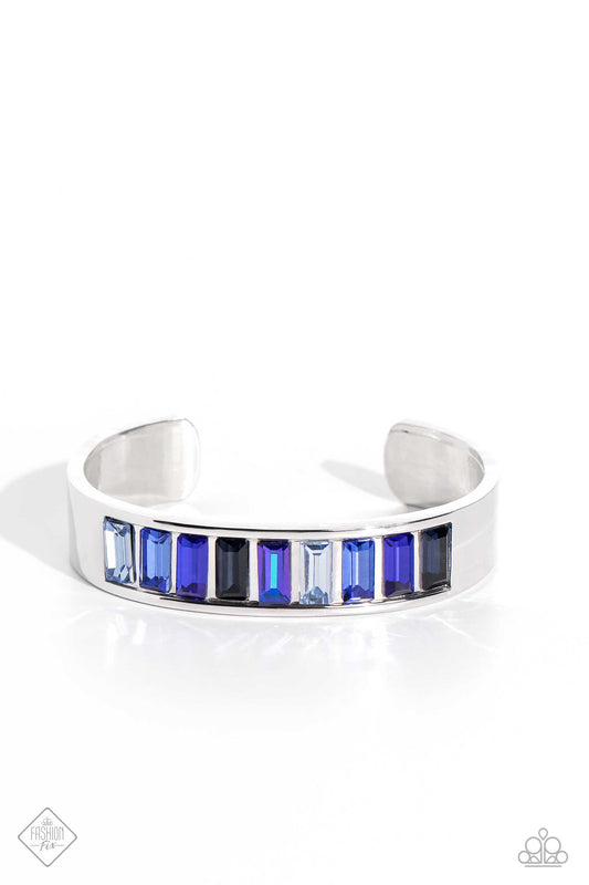Embedded in the center of a thick, high-sheen silver cuff, a row of glassy emerald-cut gems in varying shades of blue radiates atop the wrist, creating an unexpected pop of color.  Sold as one individual bracelet.