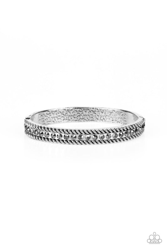 Gritty silver rope-like borders flank a glitzy row of hematite rhinestones, creating a smoldering bangle-like bracelet around the wrist. Features a hinged closure.  Sold as one individual bracelet.