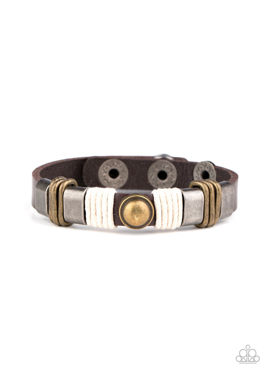 Infused with a brass studded centerpiece, gunmetal frames, brass links, and pieces of twine adorn a brown leather band for a rustic compilation. Features an adjustable snap closure.  Sold as one individual.