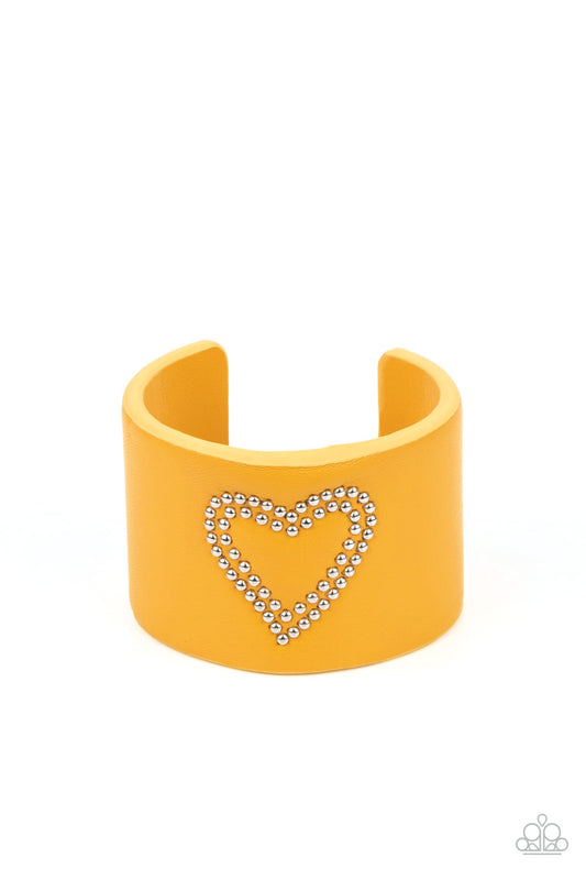 The center of a yellow leather cuff is studded in a charming heart pattern, creating a rustically romantic look around the wrist.  Sold as one individual bracelet.