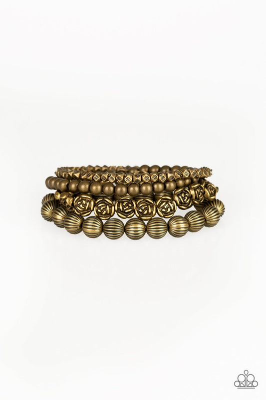 A collection of brass roses, ornate brass beads, and dainty brass accents are threaded along stretchy bands, creating whimsical layers around the wrist.

Sold as one set of four bracelets.