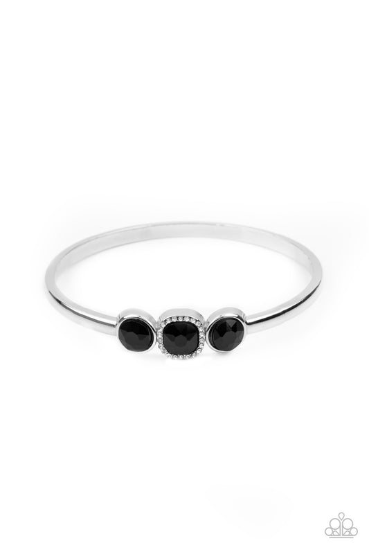 The center of a thick silver bangle has been adorned with a trio of glittery black rhinestones, creating a sparkly centerpiece around the wrist. Featuring a regal cube cut, the centermost rhinestone is bordered by a frame of glassy white rhinestones for a glamorous finish.  Sold as one individual bracelet.