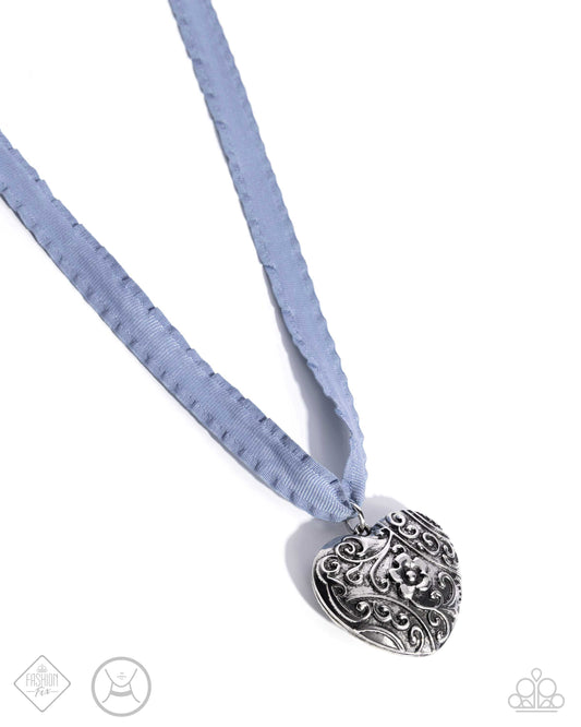 A vintage-embellished, oversized silver floral filigree heart pendant glides along a Chambray Blue scalloped ribbon for an adorably antiqued look. Features an adjustable clasp closure.  Sold as one individual necklace. Includes one pair of matching earrings.