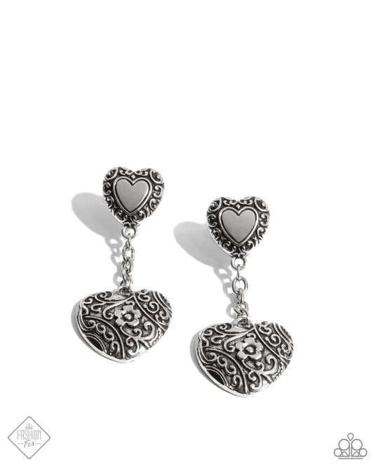 Framed in antiqued filigree, a silver heart charm gives way to a silver chain and a larger, floral filigree-embellished silver heart pendant, creating a charming rustic lure. Earring attaches to a standard post fitting.  Sold as one pair of post earrings.
