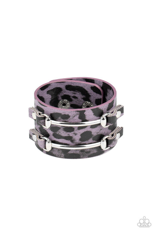 Two arcing silver bars are studded in place across the front of a thick leather band painted in purple and black cheetah print for a wild look. Features an adjustable snap closure.

Sold as one individual bracelet.