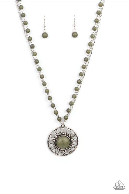 A dainty silver chain is paired with a grounding green stone beaded chain below the collar. An oversized green stone adorns the center of an antiqued silver frame radiating with silver studded and wire-like detail, creating an authentic artisan inspired pendant at the bottom of the earthy chains. Features an adjustable clasp closure.  Sold as one individual necklace. Includes one pair of matching earrings.