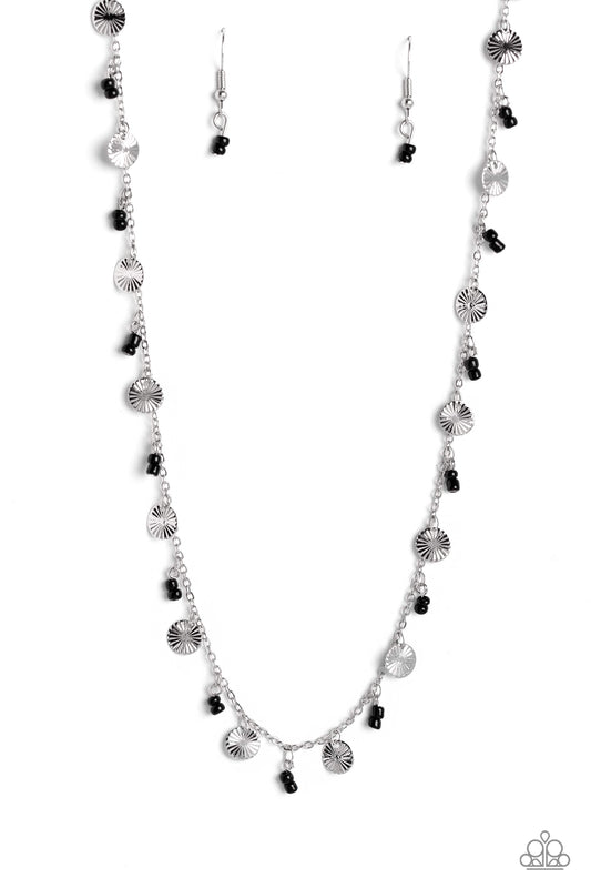 Infused along a dainty silver chain, duos of black seed beads alternate with warped, layered silver discs to make a colorful, sand-dollar-like statement down the neckline. Features an adjustable clasp closure.  Sold as one individual necklace. Includes one pair of matching earrings.